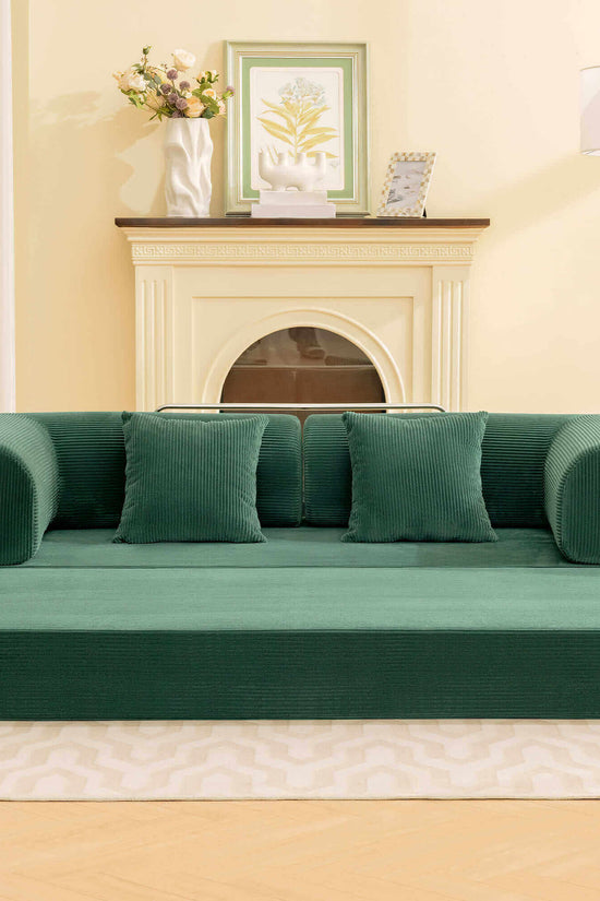 Primyhome Modern convertible green corduroy floor sofa bed in a cozy living room setting with a wooden floor lamp and framed botanical art.
