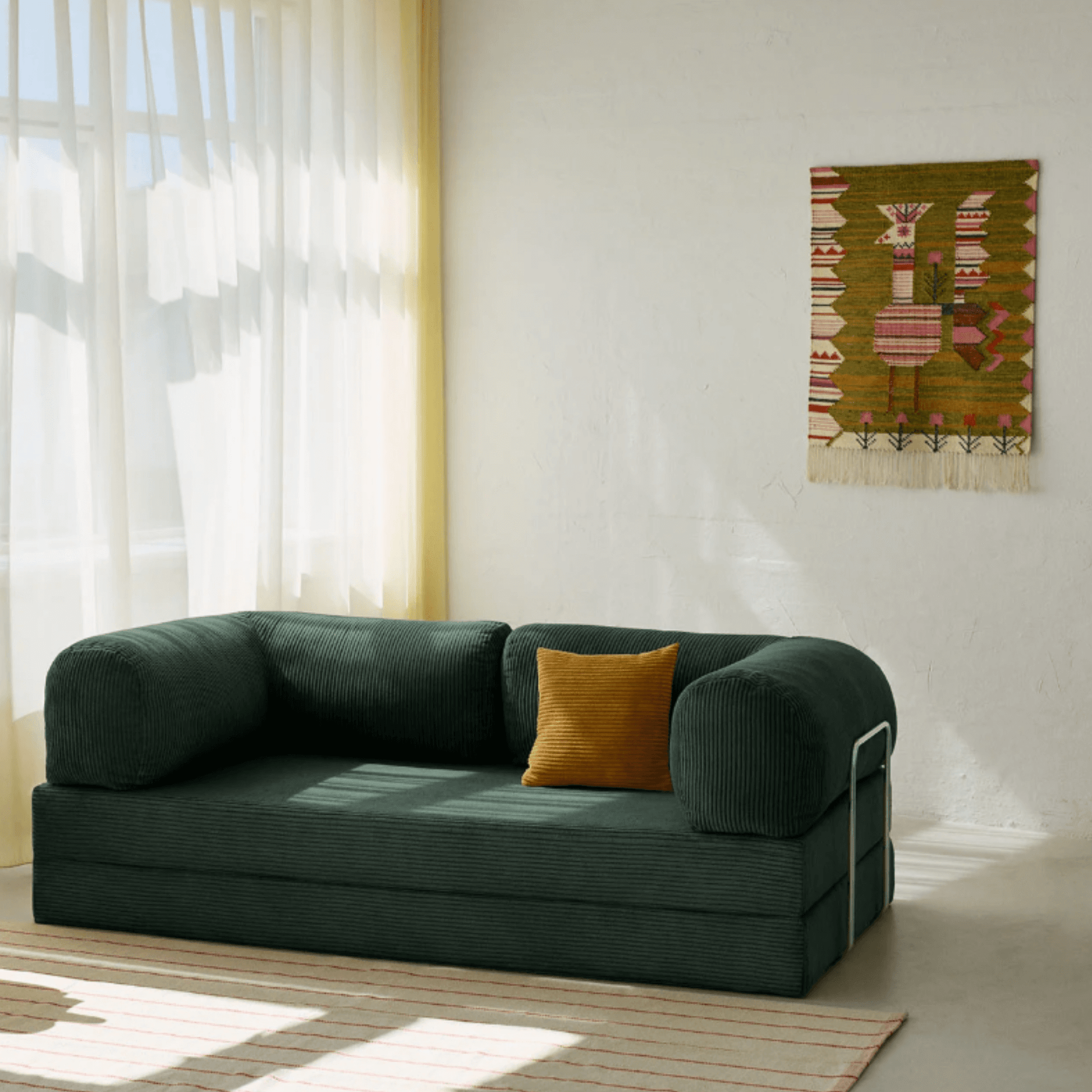 Primyhome green corduroy convertible sofa bed in a sunlit living room with minimalist decor and boho wall art